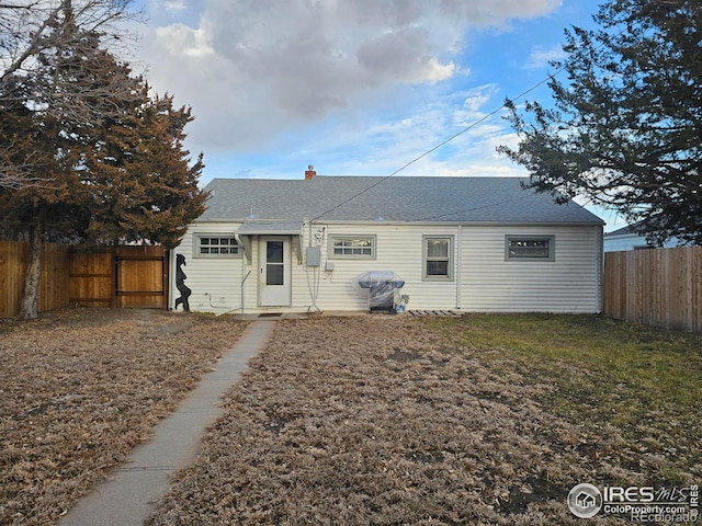 ranch-style home with a fenced backyard, a chimney, and roof with shingles