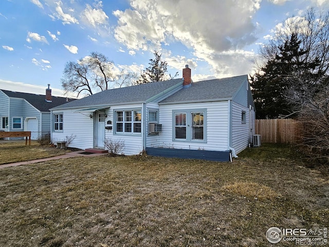 view of front of house featuring a shingled roof, a chimney, fence, central air condition unit, and a front lawn