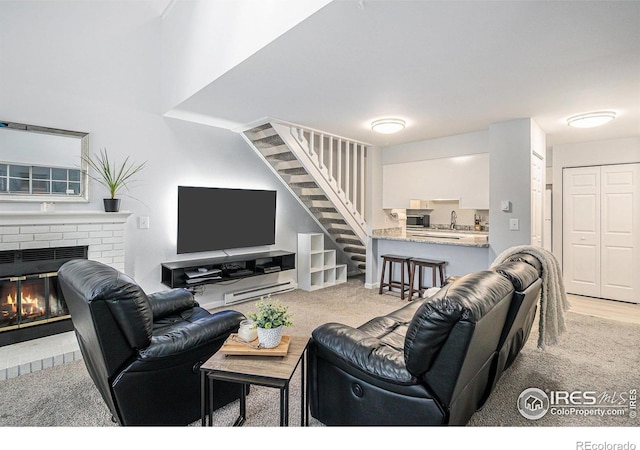 living area with a brick fireplace, carpet, and stairway