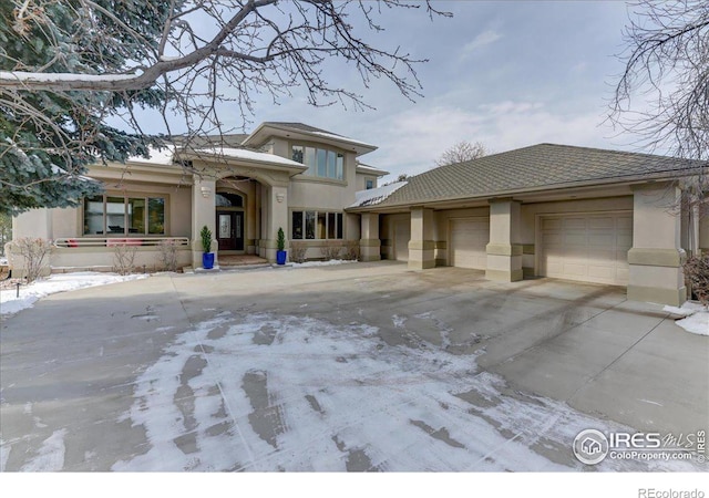 prairie-style house with a garage, driveway, and stucco siding