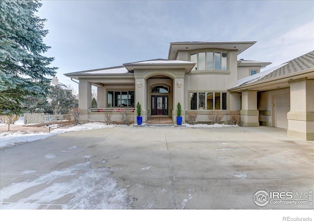 prairie-style home featuring driveway, an attached garage, and stucco siding