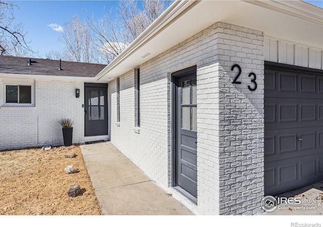 doorway to property featuring brick siding and an attached garage