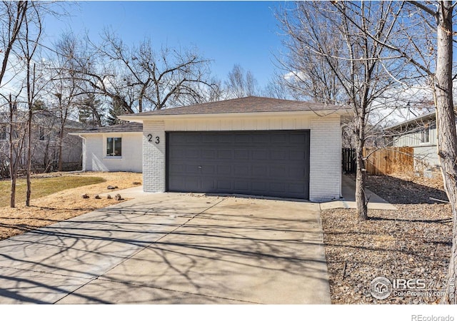 view of front of home with concrete driveway, brick siding, fence, and an attached garage