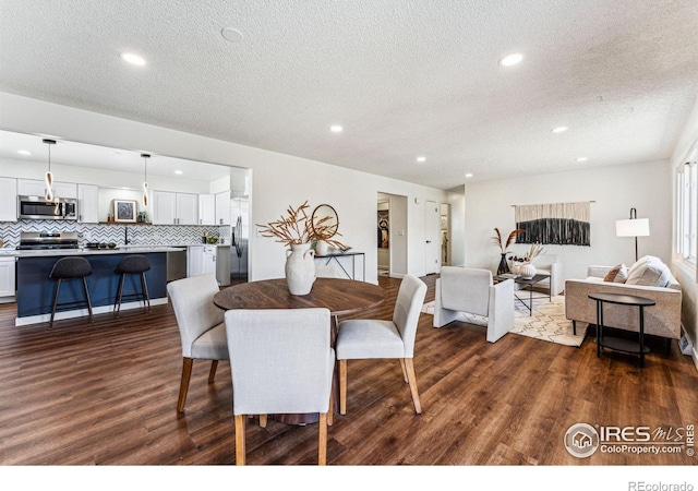 dining area with dark wood-style floors, a textured ceiling, and recessed lighting