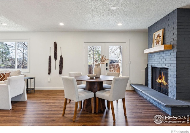 dining room featuring a fireplace, baseboards, dark wood-type flooring, and french doors