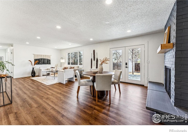 dining room featuring plenty of natural light, french doors, dark wood finished floors, and a brick fireplace