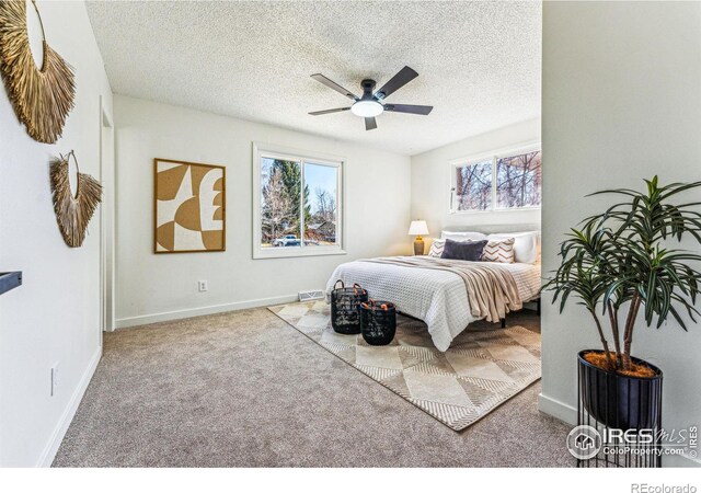 bedroom with visible vents, light carpet, a textured ceiling, and baseboards