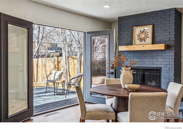 dining room featuring visible vents, a fireplace, a textured ceiling, and wood finished floors