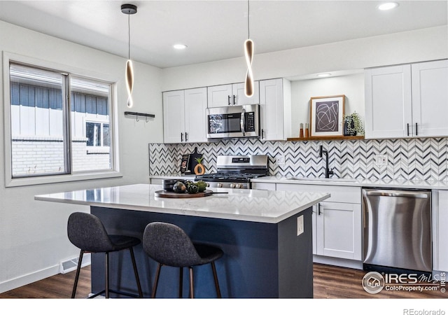 kitchen featuring stainless steel appliances, hanging light fixtures, and light countertops