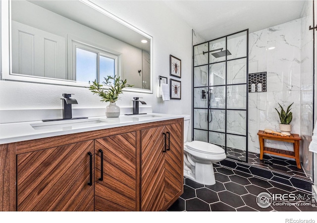 bathroom featuring toilet, a sink, a marble finish shower, and double vanity