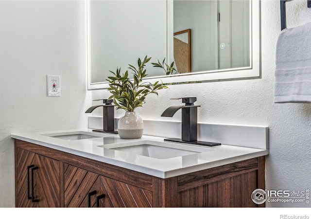 interior space with a textured wall, double vanity, and a sink