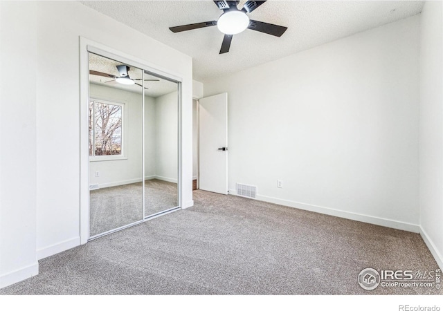 unfurnished bedroom featuring baseboards, visible vents, a textured ceiling, carpet flooring, and a closet