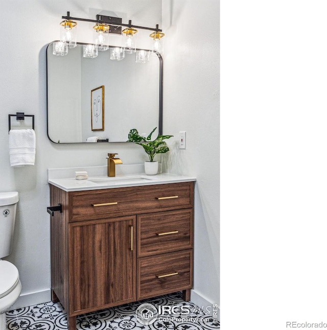 bathroom with toilet, tile patterned floors, baseboards, and vanity