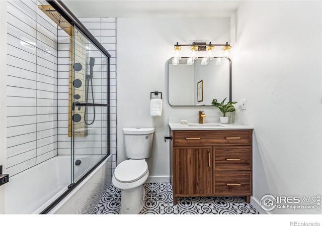 bathroom featuring toilet, combined bath / shower with glass door, vanity, tile patterned flooring, and baseboards