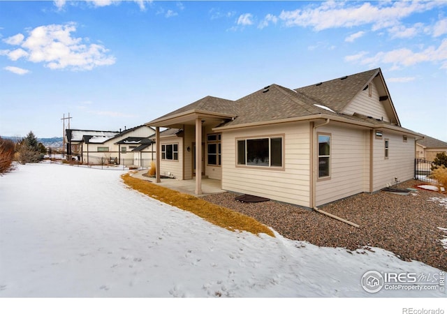 snow covered property with a shingled roof