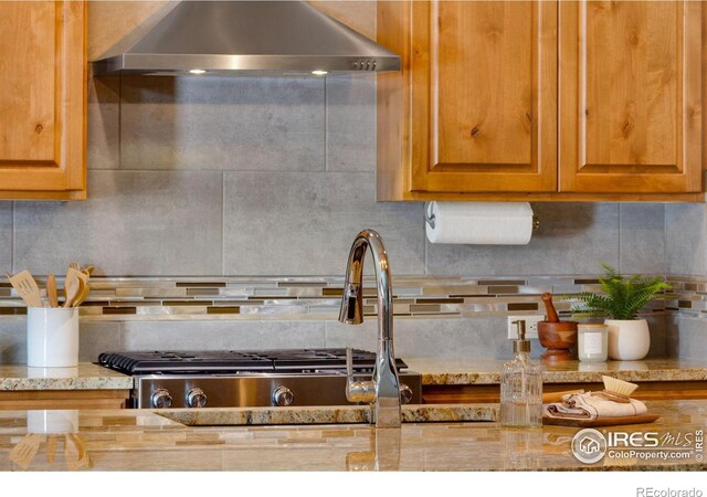 kitchen featuring wall chimney range hood, tasteful backsplash, and brown cabinetry