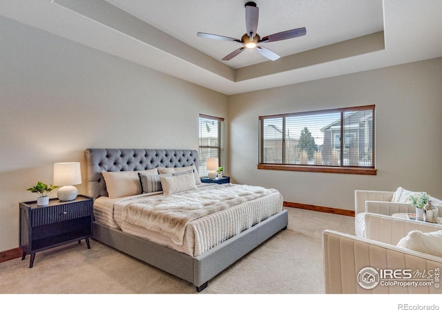 bedroom with carpet floors, baseboards, a raised ceiling, and a ceiling fan