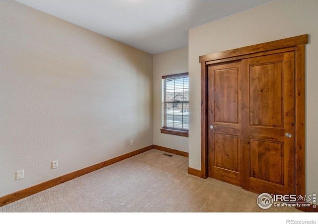 unfurnished bedroom featuring light carpet, visible vents, and baseboards