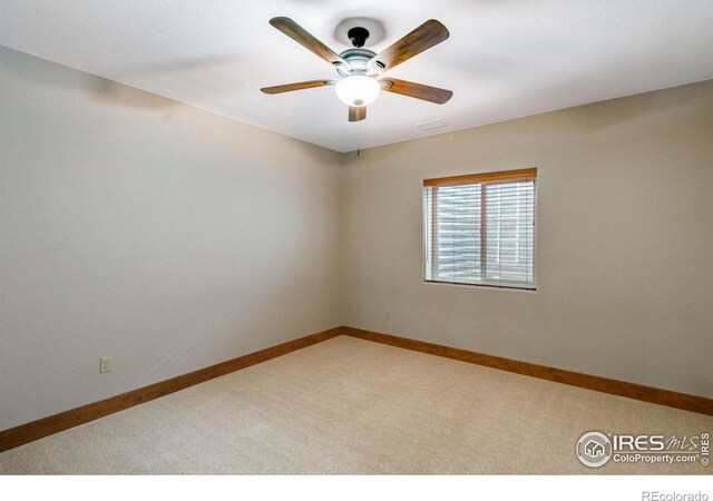 spare room featuring baseboards, a ceiling fan, and light colored carpet