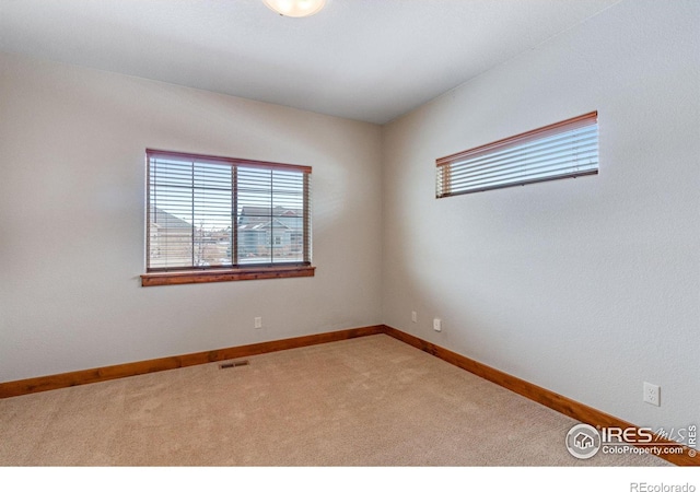 carpeted spare room featuring visible vents and baseboards