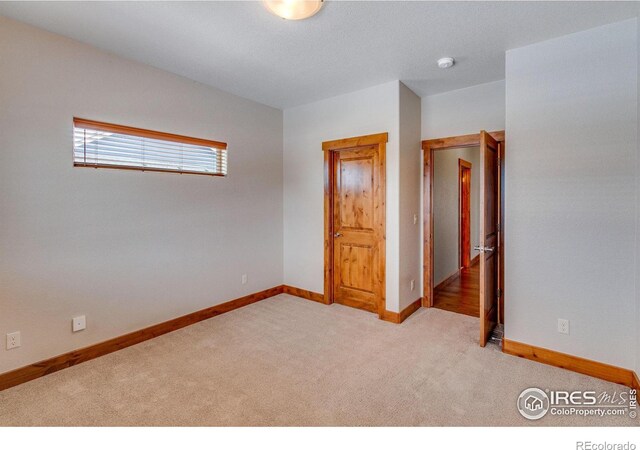 unfurnished bedroom with light colored carpet and baseboards