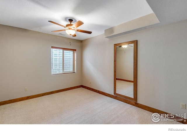 empty room with carpet, visible vents, ceiling fan, and baseboards