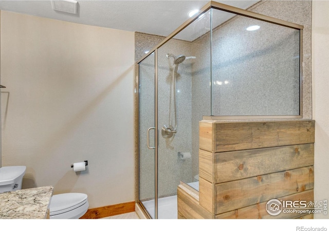 bathroom with toilet, a shower stall, and vanity