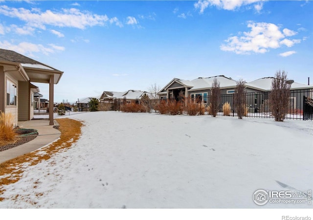 snowy yard with a residential view and fence