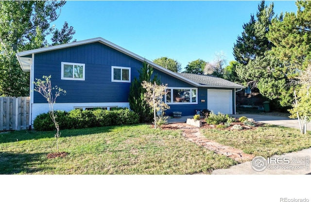 split level home featuring a garage, a front yard, driveway, and fence