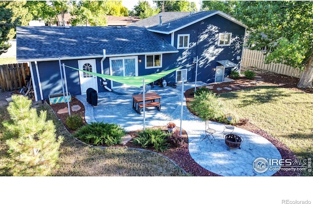 rear view of property with a patio, an outdoor fire pit, a shingled roof, and fence