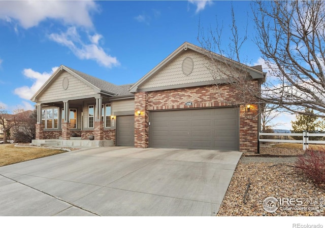 view of front facade featuring a porch, a garage, brick siding, fence, and concrete driveway