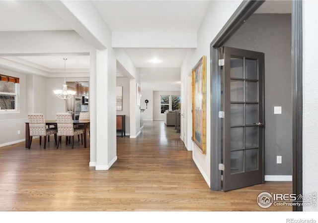 foyer entrance with a chandelier, wood finished floors, and baseboards