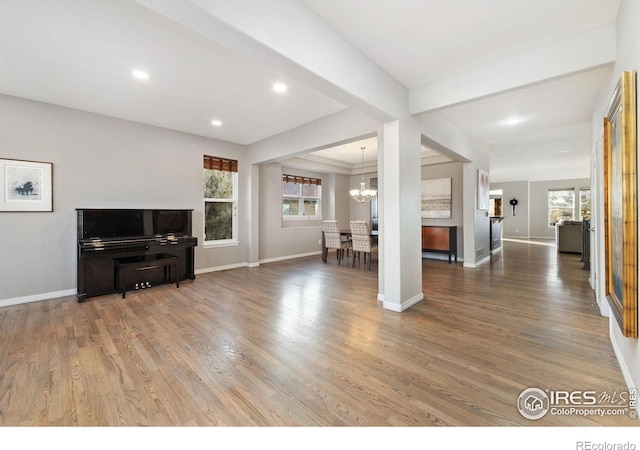 living area with a wealth of natural light, baseboards, and wood finished floors