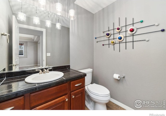 bathroom featuring baseboards, vanity, and toilet