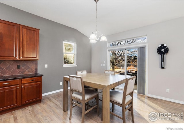 dining area featuring light wood finished floors, baseboards, vaulted ceiling, and a wealth of natural light