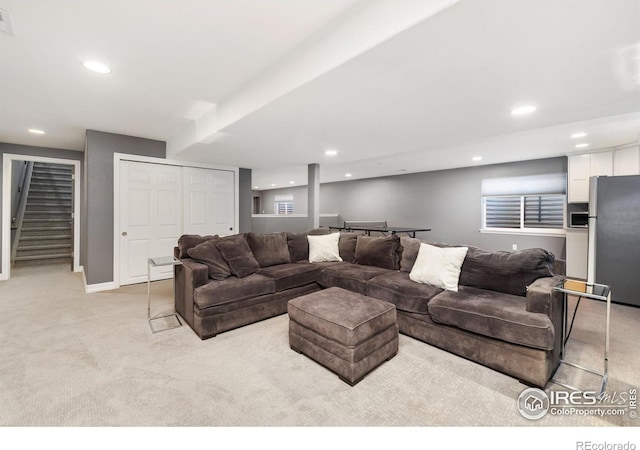 living room with recessed lighting, light colored carpet, baseboards, and stairs