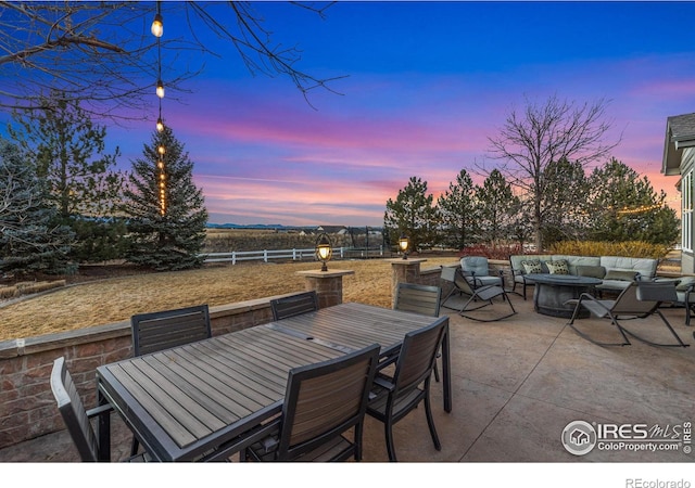 patio terrace at dusk with outdoor dining area, fence, and an outdoor living space