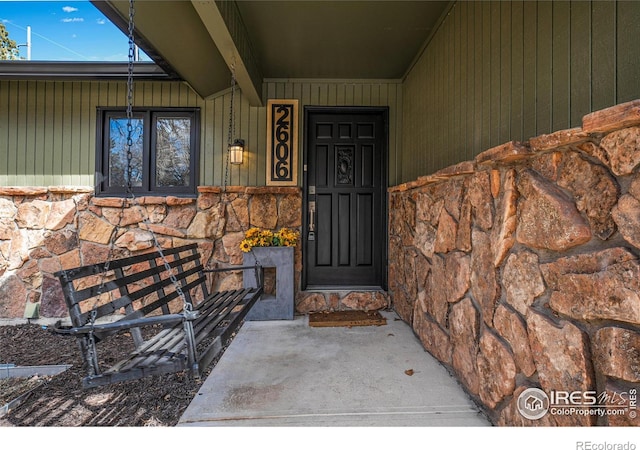 view of exterior entry featuring covered porch and stone siding