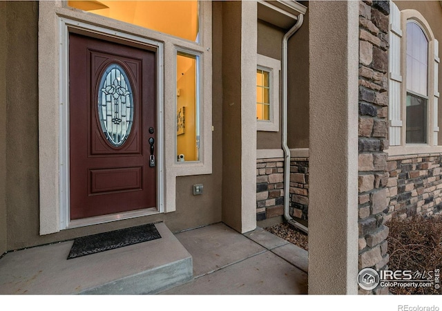 property entrance featuring stone siding and stucco siding