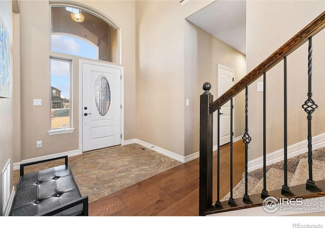 entrance foyer featuring stairs, dark wood-type flooring, and baseboards