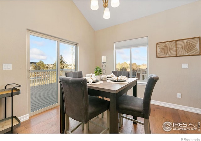 dining space featuring high vaulted ceiling, an inviting chandelier, wood finished floors, and baseboards