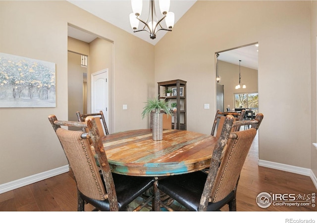 dining room featuring dark wood-style floors, baseboards, high vaulted ceiling, and an inviting chandelier