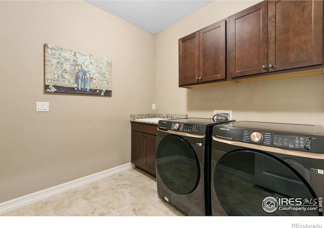 clothes washing area with cabinet space, washing machine and dryer, baseboards, and a sink