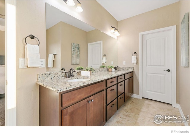 bathroom with double vanity, a sink, and baseboards