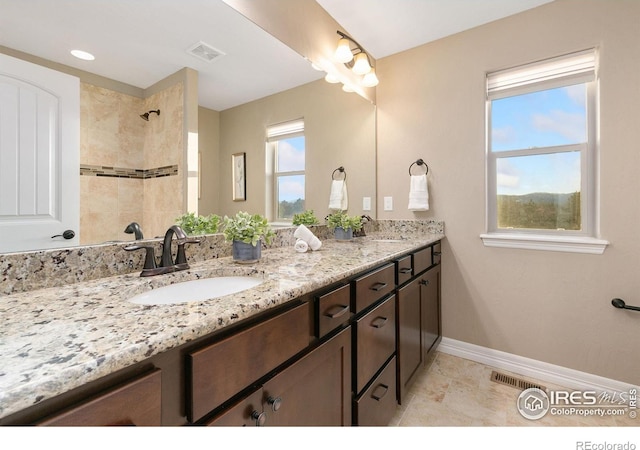 full bath with double vanity, baseboards, visible vents, and a sink