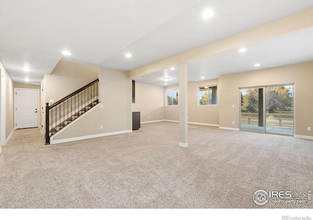 below grade area with light colored carpet, baseboards, and stairs