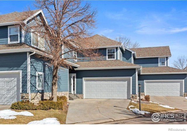 view of front of property featuring a garage, driveway, a shingled roof, entry steps, and stone siding