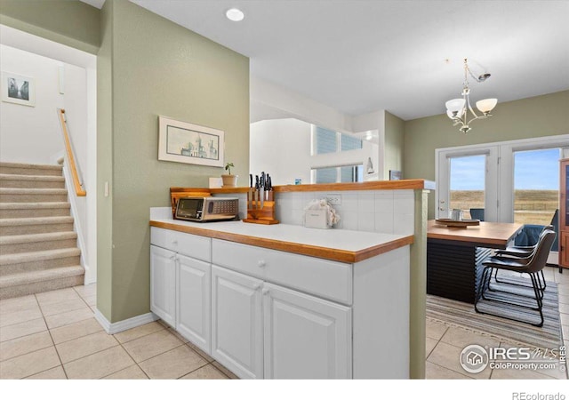 kitchen with light tile patterned floors, white cabinets, hanging light fixtures, an inviting chandelier, and light countertops