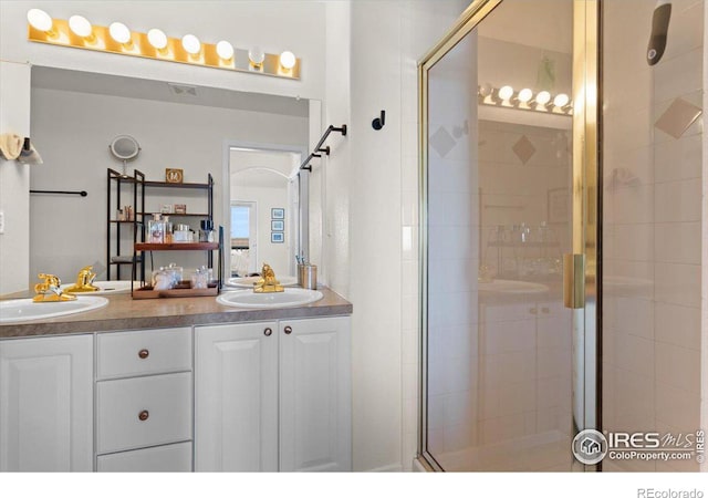 full bathroom with double vanity, a shower stall, and a sink