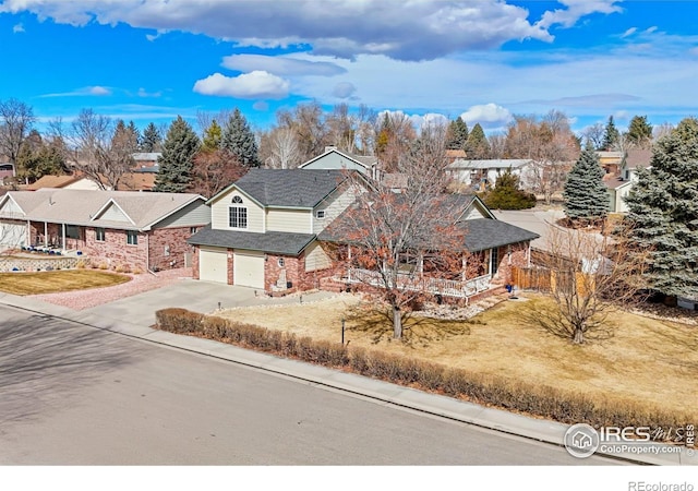 traditional-style house with an attached garage, driveway, a residential view, and a front lawn